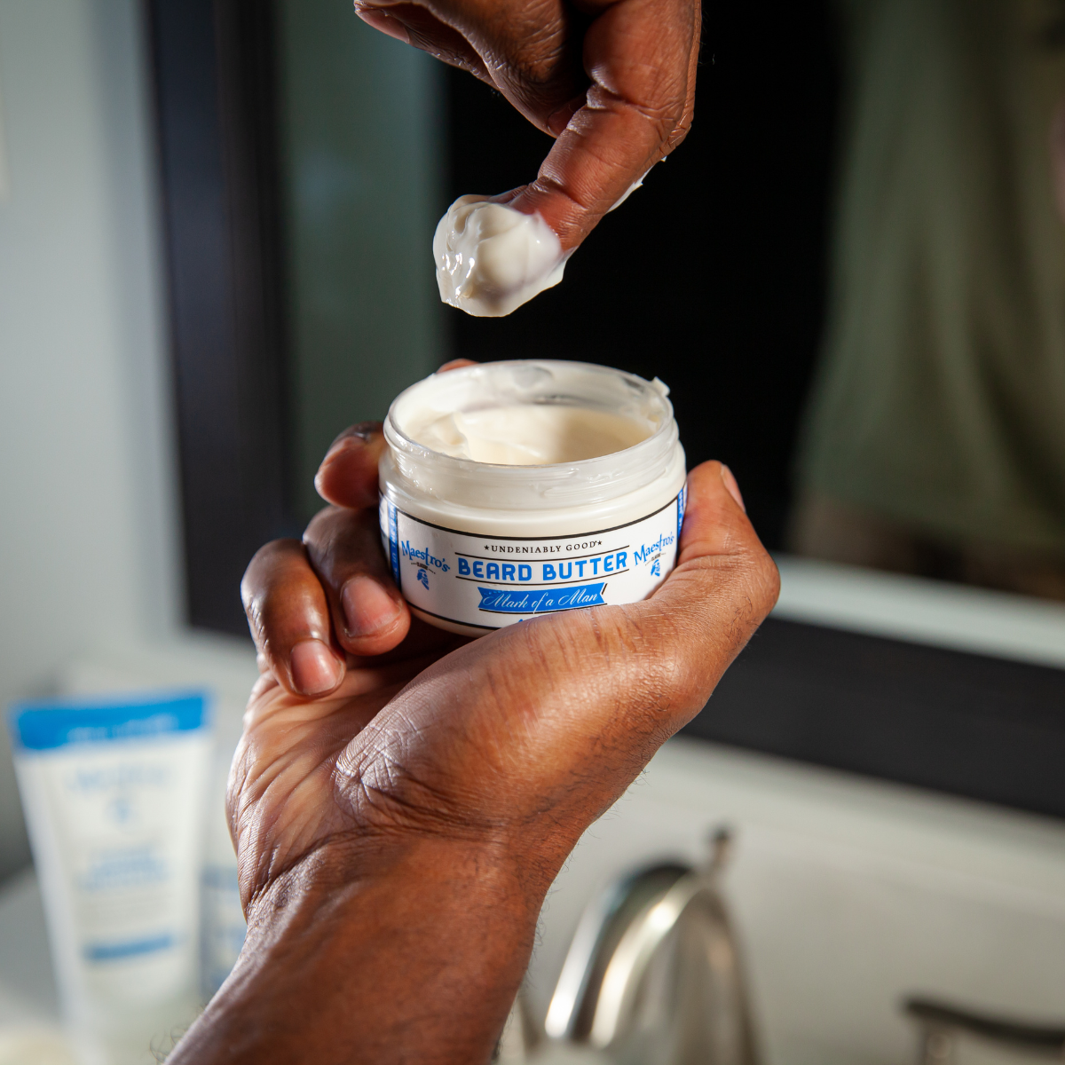 Hand scooping beard butter from a jar with a blurred background