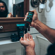 Person holding a bottle of speakeasy beard wash over their hand in a bathroom.